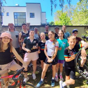 Gruppenfoto der Triathlon-Jugend von MACH3 Köln e.V. beim DIY-Rennrad-Workshop vor der Werkstatt von Velonia. Kinder, Jugendliche und Trainer lächeln mit Werkzeug und Fahrrädern fröhlich in die Kamera.